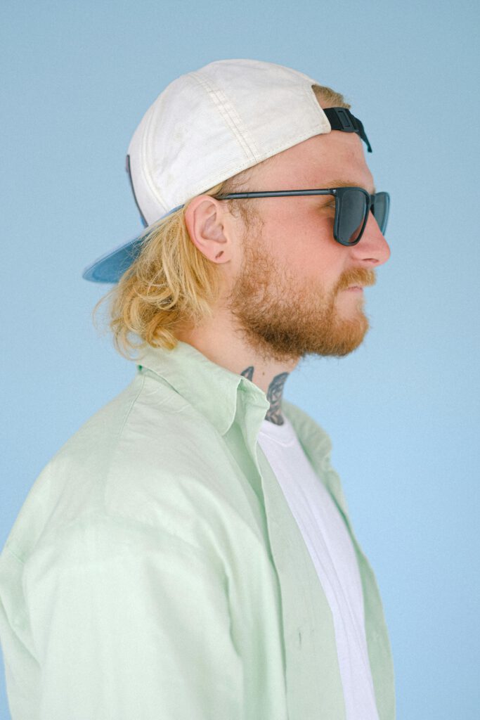 Photo de Julien Moreau de profil avec une casquette blanche sur fond bleu.